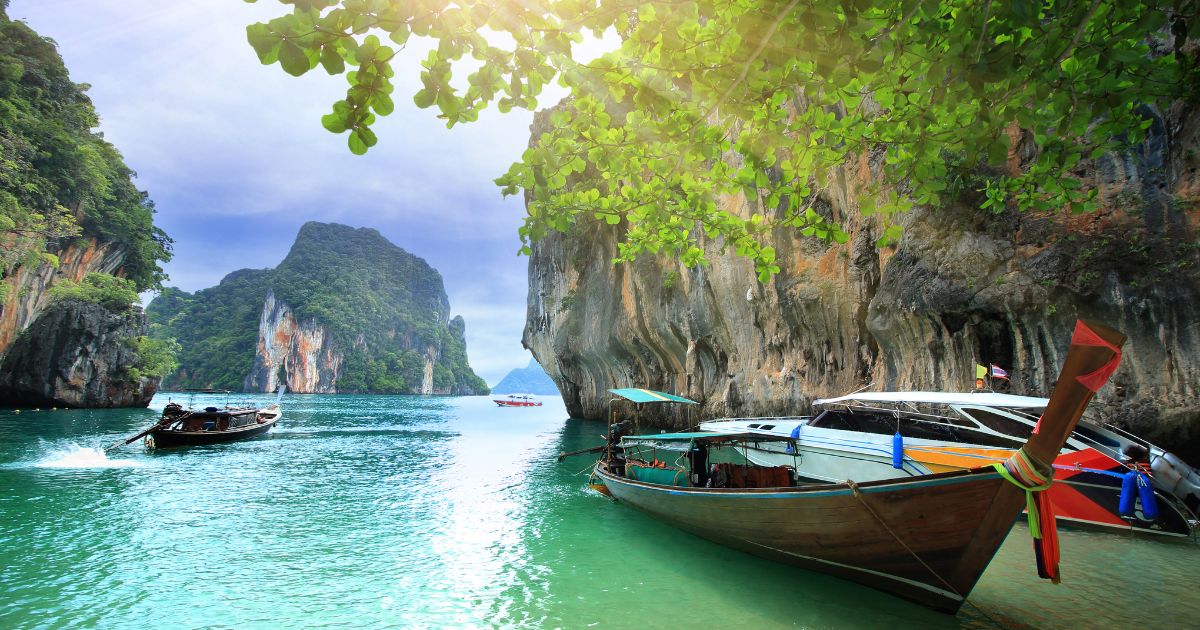 Barco en la playa de Railay con acantilados rocosos al fondo