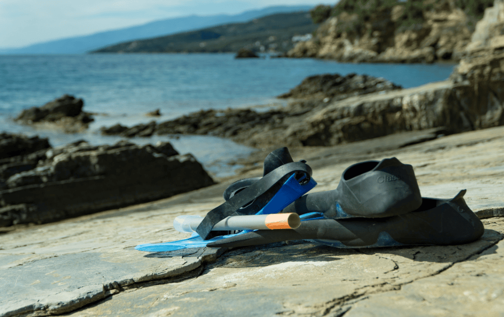 esnórquel y máscara descansando sobre una roca con vistas al mar al fondo