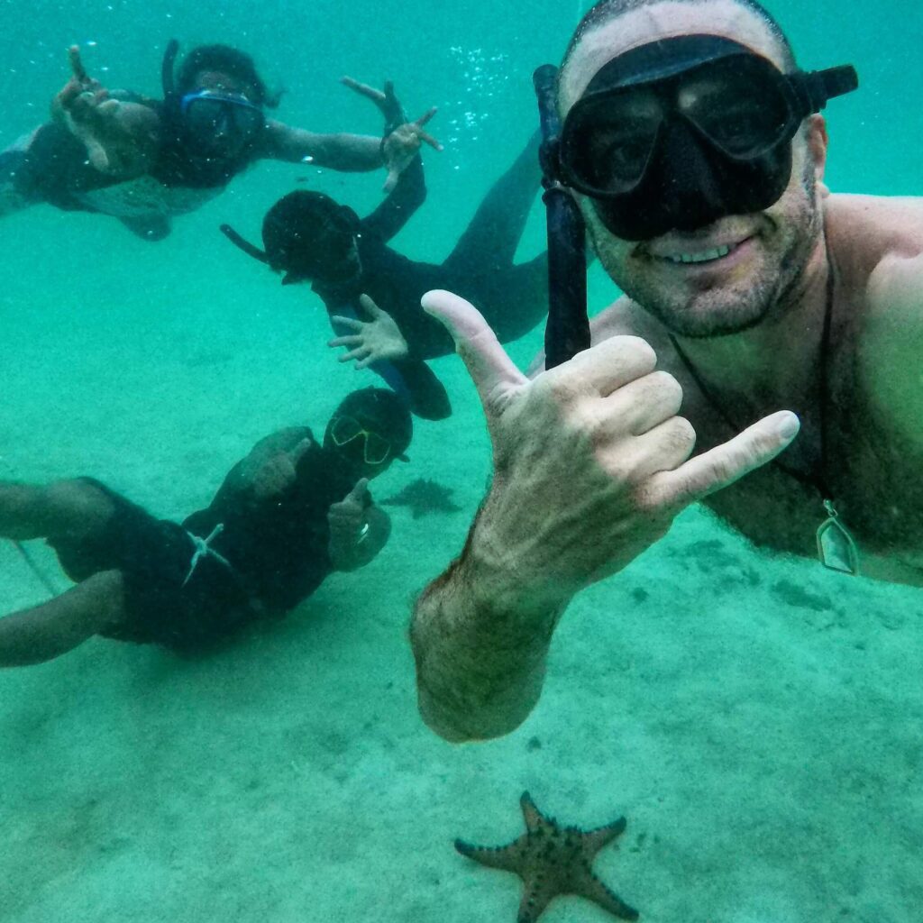 cuatro buceadores en apnea tomándose un selfie con una estrella de mar lagre en el fondo del mar en krabi
