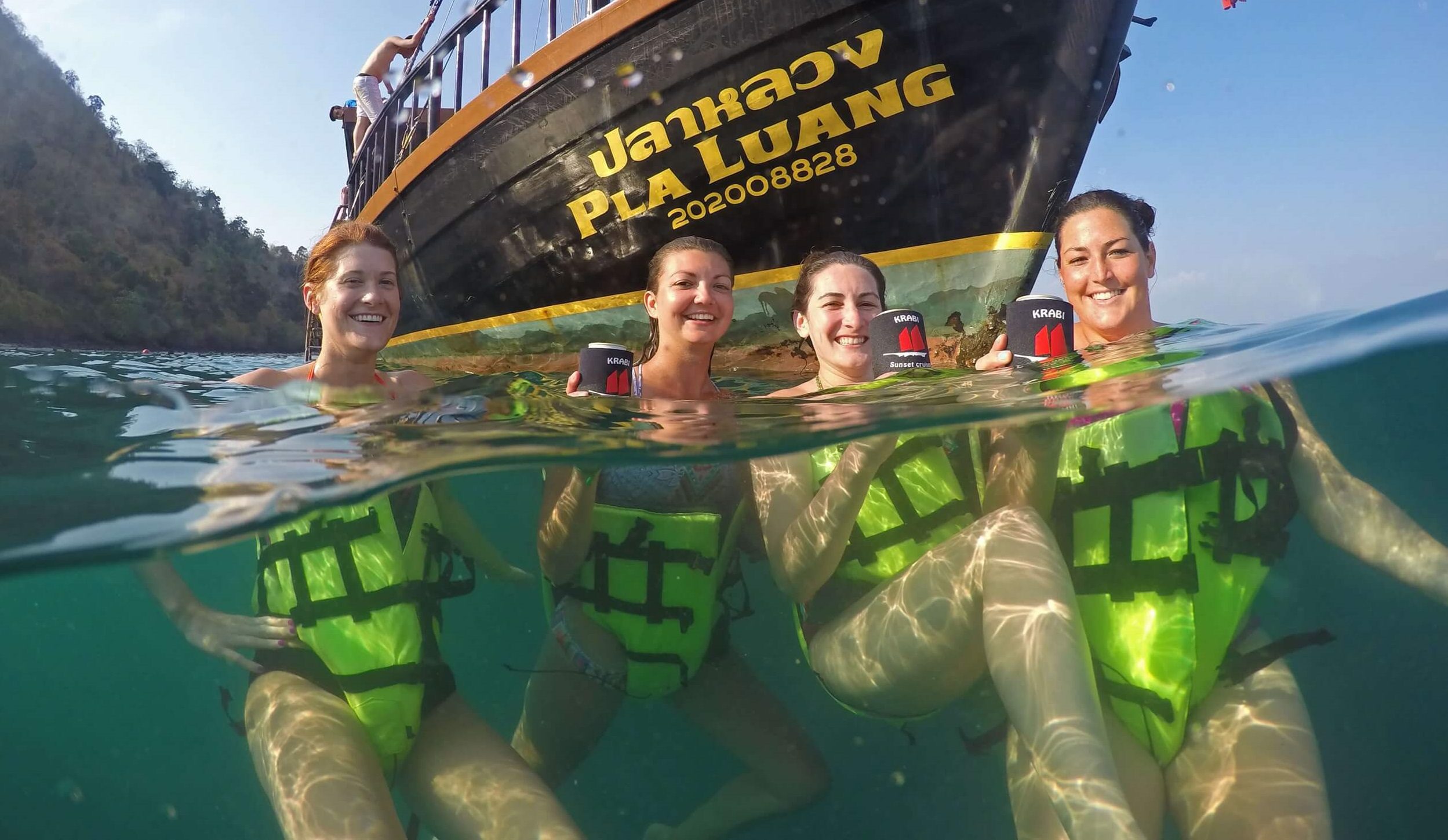 4 personas en el agua con krabi sunset cruises barco en el fondo