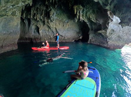 Los huéspedes practican paddleboarding y snorkel en una cueva marina de piedra caliza en Koh Si