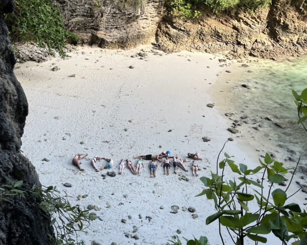una vista de pájaro de gente deletreando la palabra contiki en la playa con sus cuerpos
