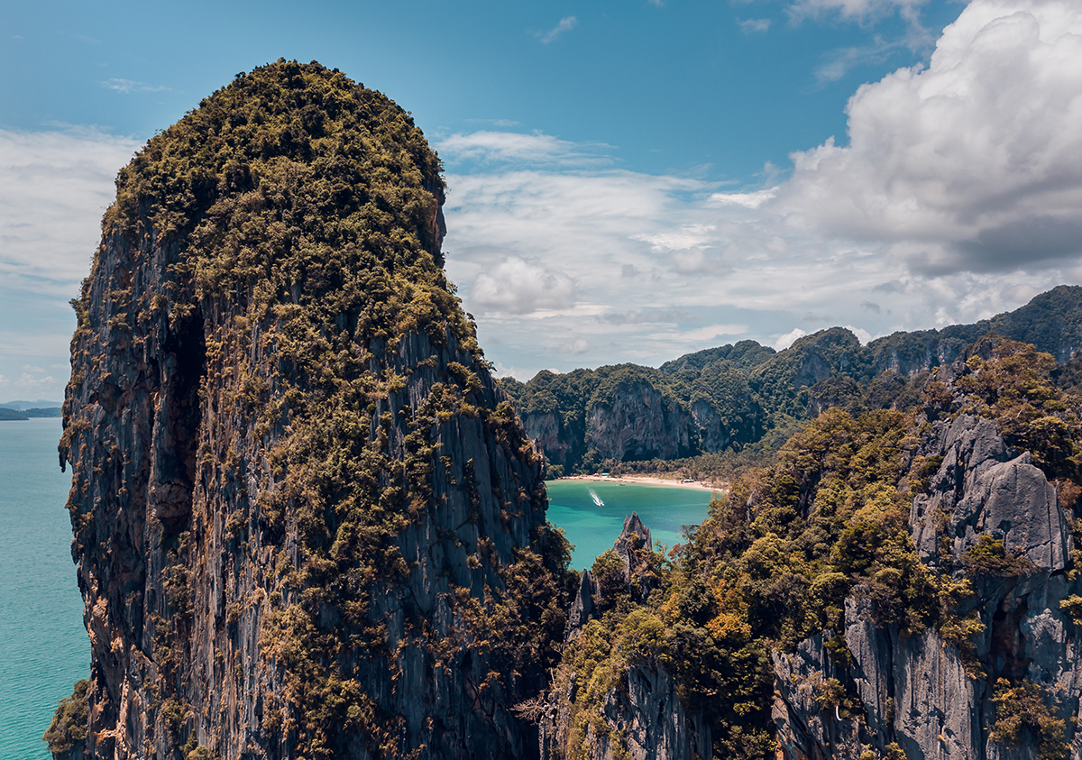 Falaises de calcaire de Railay : vue du haut d'une des falaises avec un aperçu de la plage ouest de Railay entre les rochers.