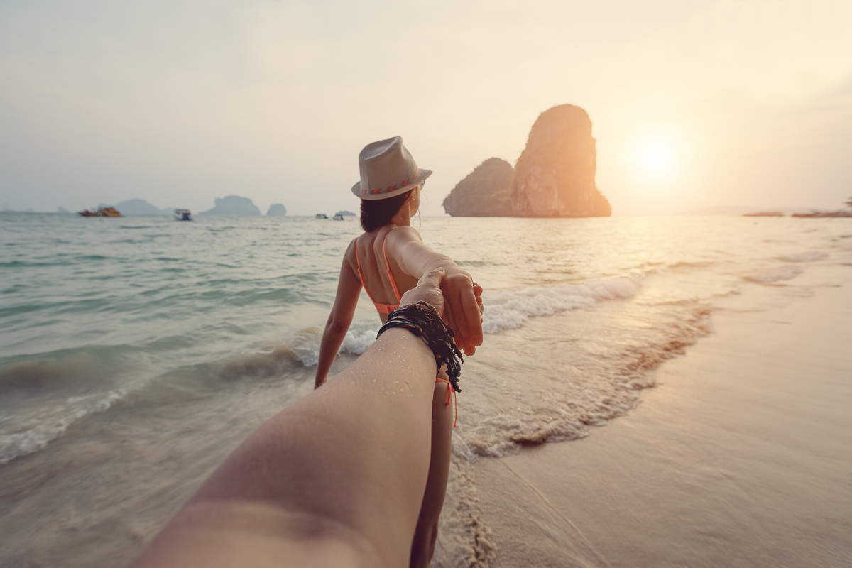pov de un hombre que coge la mano de una mujer. ella esta en el mar en la playa de Railay mirando hacia las islas de Krabi