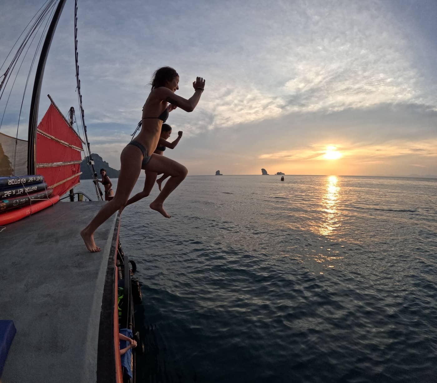 Des passagers sautant du bateau de « Krabi Sunset Cruises » dans la mer au coucher du soleil à Krabi, en Thaïlande