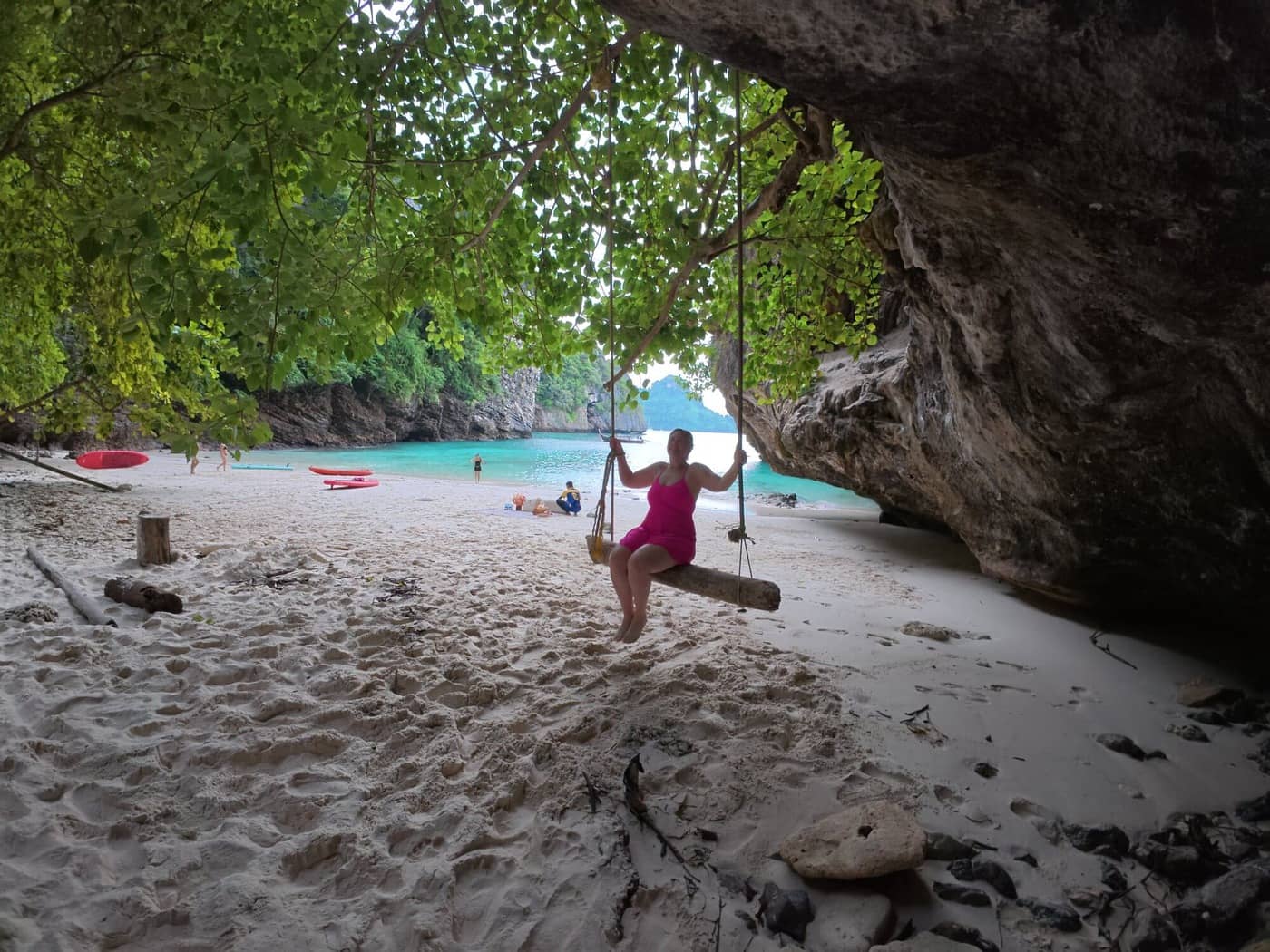 Guest relaxing on a wooden swing at a secluded tropical beach reached during a private Krabi cruise.
