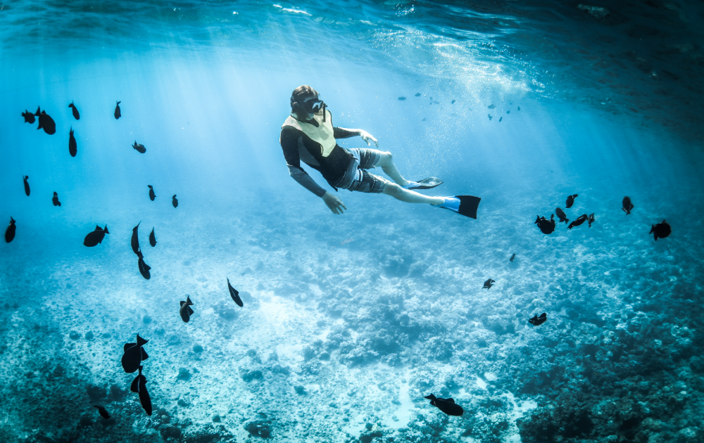 homme faisant de la plongée avec masque et tuba en eau profonde, entouré de poissons