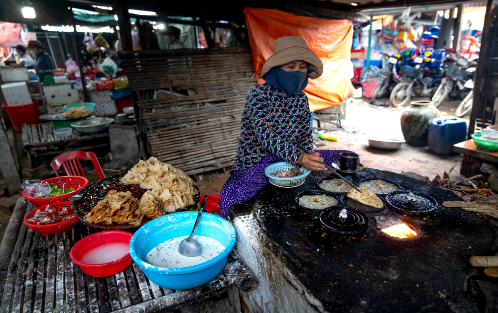 femme préparant des aliments thaïlandais locaux sur une grande plaque chauffante dans un marché