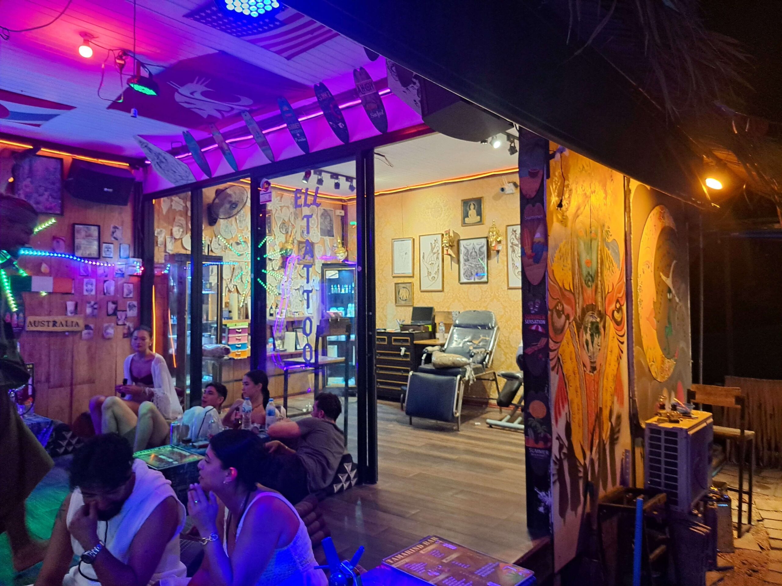 vue de l'intérieur d'un salon de tatouage à railay, krabi. la porte est ouverte et il y a des clients du bar assis à l'extérieur