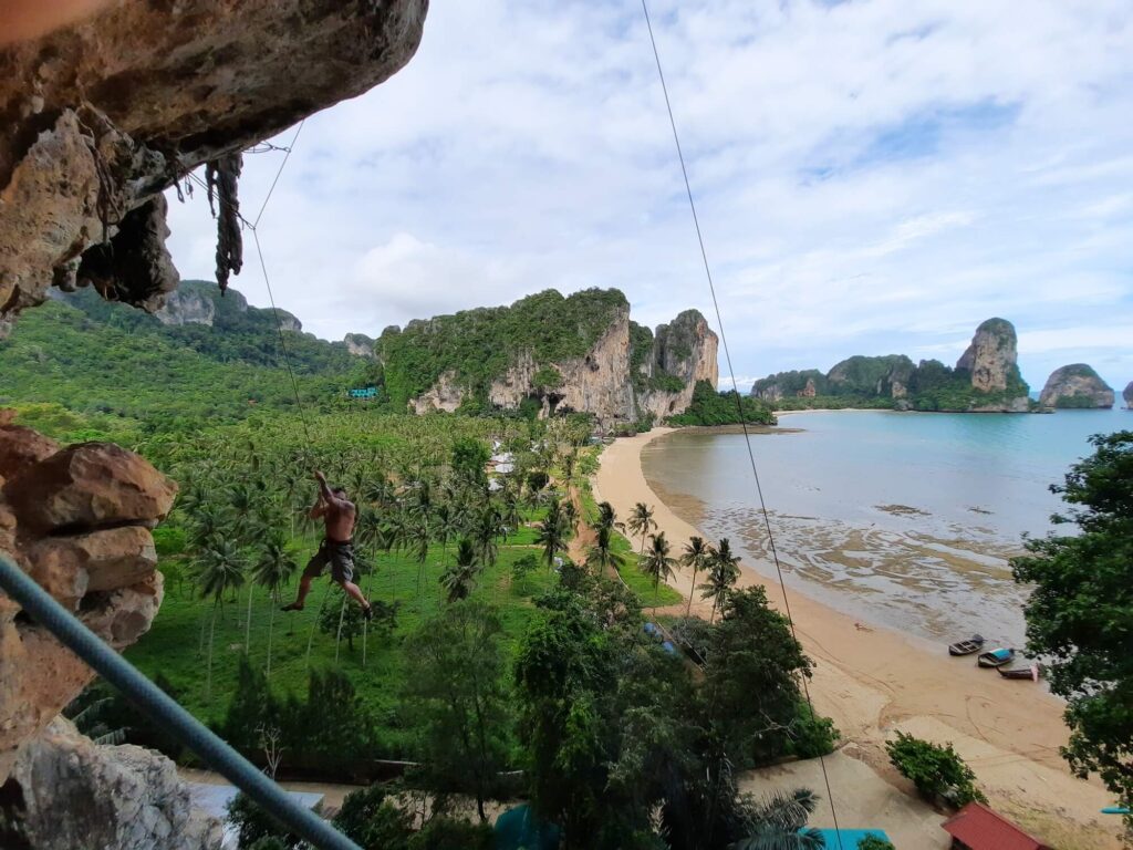 views over tonsai beach fro the cliffs with a rock climber hanging in open space