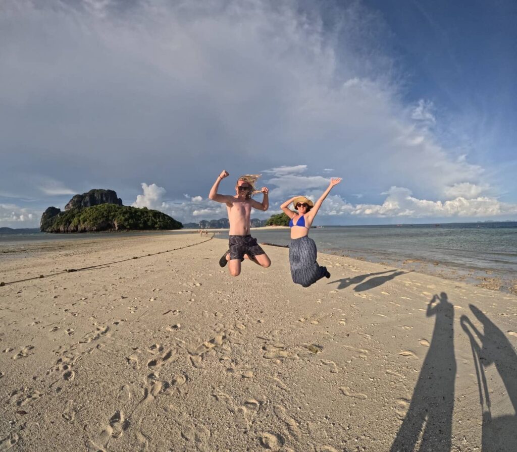 A couple jumping on the sandbar that links Chicken island and Tub island in Krabi.