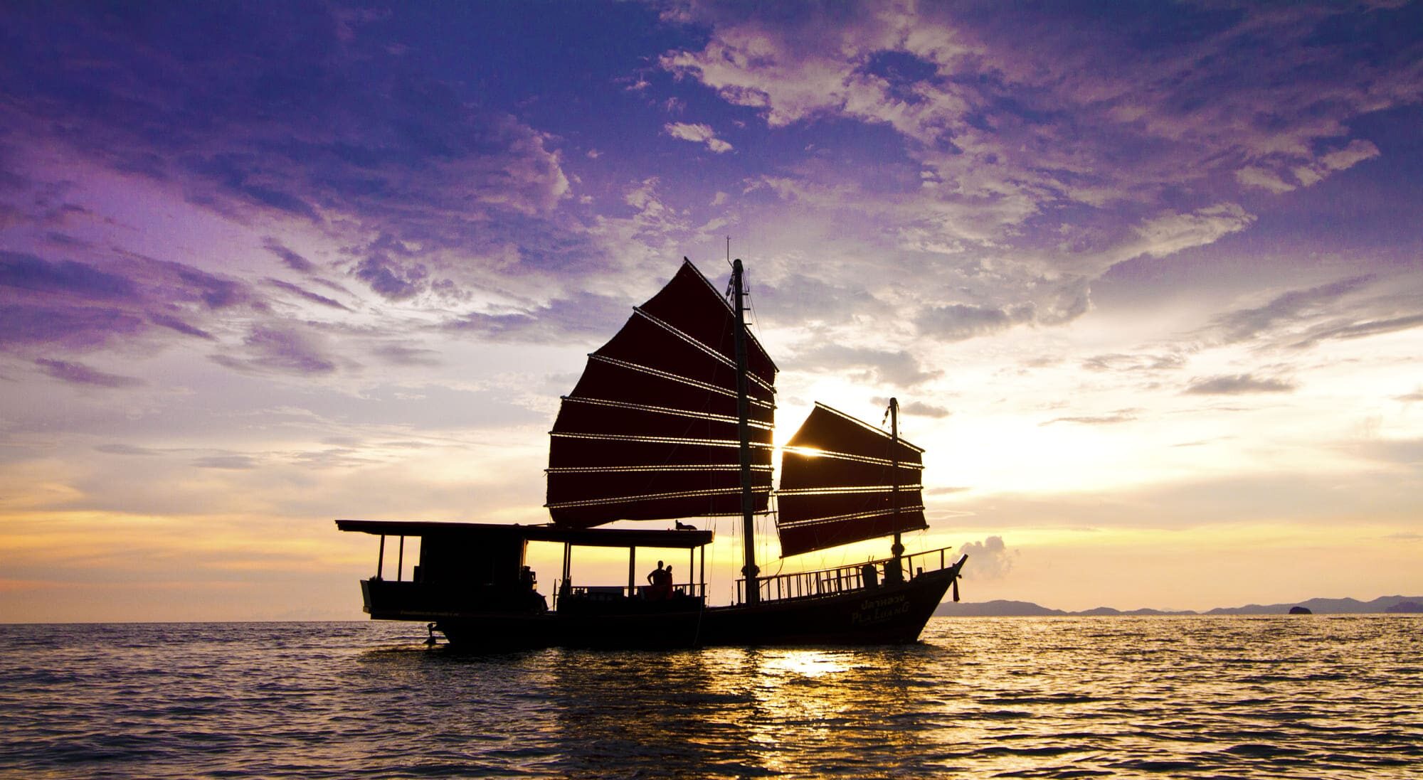 Junk boat sailing at sunset in the Andaman sea