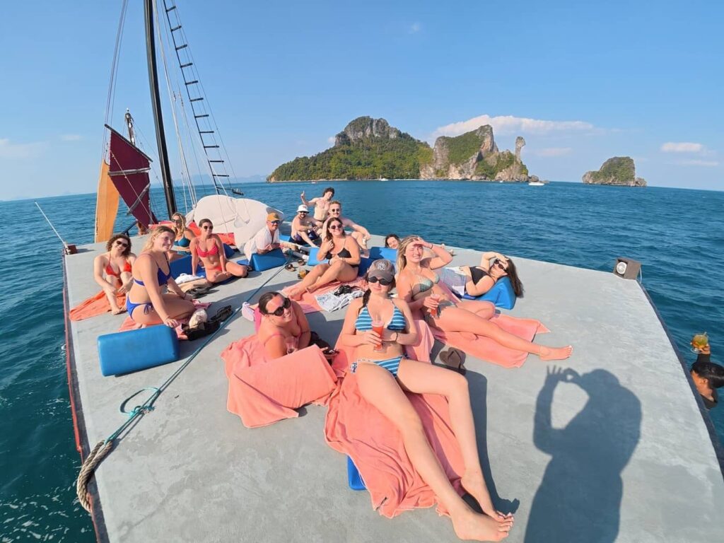 Guests relaxing on the spacious rooftop deck of Pla Luang with limestone islands and the Andaman Sea in the background.